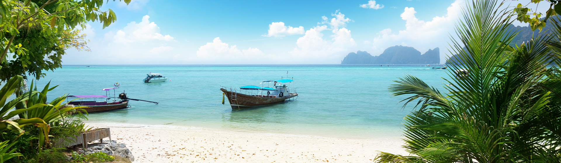 A traditional Thai boat docked at a secluded bay with striking karsts in the ocean, Thailand